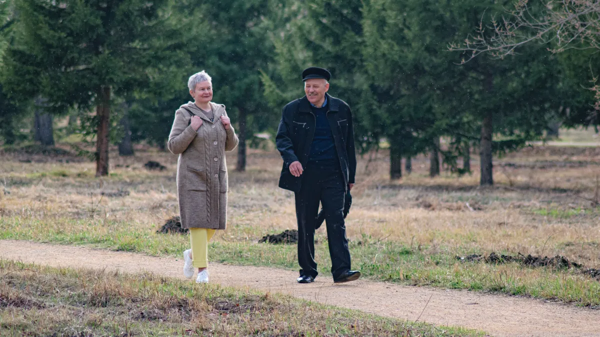 Happy senior couple strolling along a park path on a pleasant spring day.