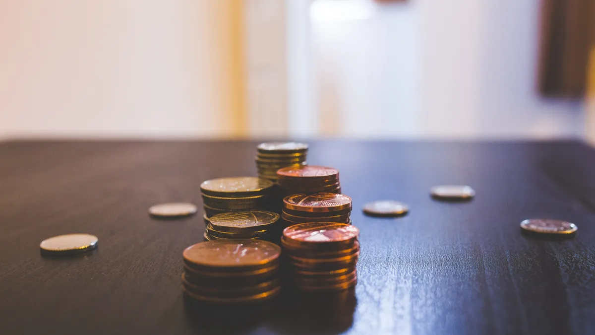 Close-up of various coins stacked on a dark table indoors.
