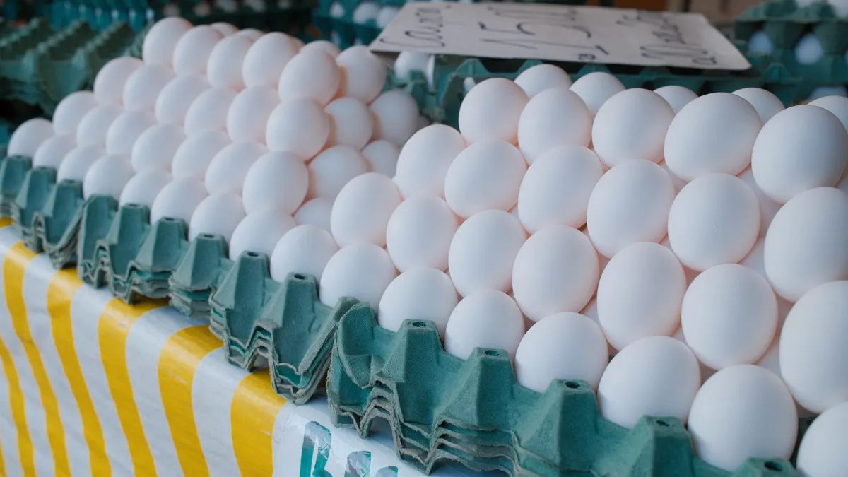Stacks of fresh white eggs on a green carton tray at a local market. Ideal for culinary themes.