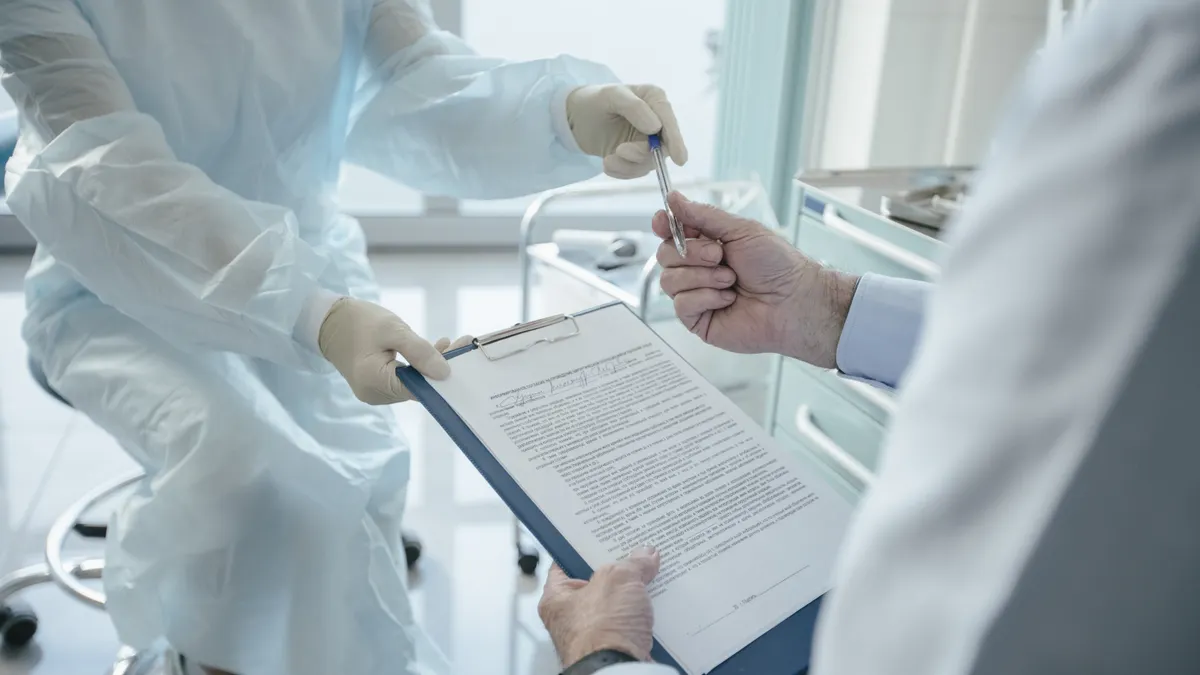 A doctor hands a clipboard to a patient for signature, highlighting medical professionalism.